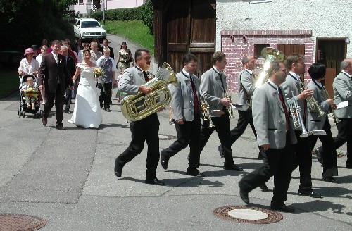 Das Ehepaar Schweizer und der Musikverein beim Hochzeitszug zur St.-Johannes-Kirche
